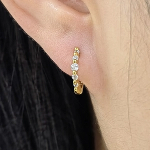 Close-up of a gold-plated sterling silver hoop earring with six prong-set cubic zirconia