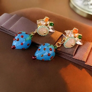 Elegant blue strawberry earrings with crystal accents on a vintage velvet background