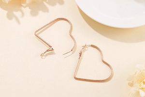 Macro shot of rose gold heart-shaped earrings with spiral twisted rope texture detail