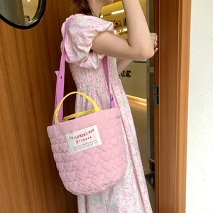 Grand sac cabas matelassé rose avec anses jaunes et bandoulière porté par un mannequin
