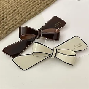 Close-up of polished resin bow hair clips in coffee brown and cream white finish