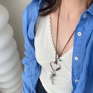 Détail d'un collier en coton vintage avec mousqueton en cœur et breloque fleur bleue