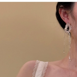 Detail of silver drop earrings with crystal round pendant and long metal tassels
