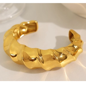 Detailed close-up showing the irregular molten lava texture on the gold wave bangle