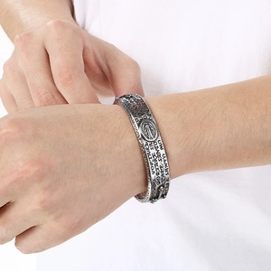 Detailed close-up of retro silver stainless steel bangle with Latin relief on wrist