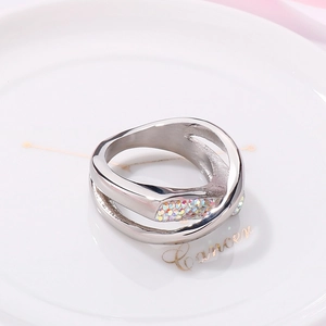 Detail of silver crisscross ring with colorful rhinestones on a white ceramic plate
