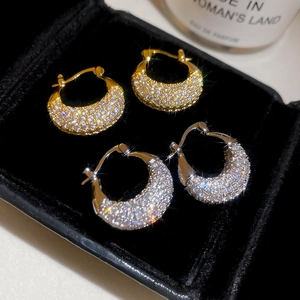 Close-up of gold and silver pavé zircon hoop earrings on a black velvet jewelry box
