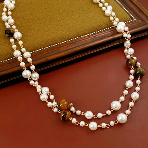 Macro view of vintage beaded necklace with tiger eye stones and white faux pearls