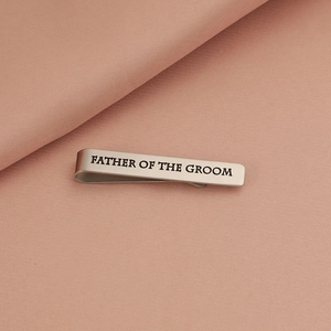 Detail of silver tie clip with Father of the Groom engraving on textured fabric