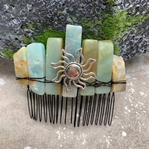 Macro shot of handmade hair comb with amazonite stones and sun charm on mossy rock