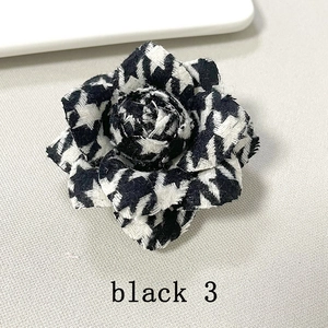 Detail of handmade houndstooth camellia brooch with layered black and white fabric petals