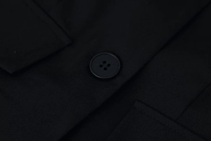 Detailed macro view of black twill fabric texture and four-hole button on the long sleeve jacket