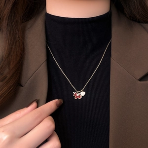 Close-up of model wearing a gold horse necklace with red enamel and heart pendant details