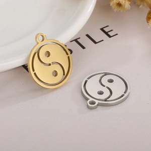 Detailed view of round gold and silver Tai Chi Yin Yang fish pendants on a neutral surface