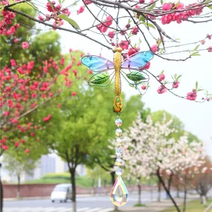 Detail of dragonfly suncatcher with crystal prisms hanging on a flowering branch