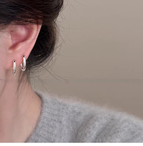 Orecchini a cerchio ovali in argento lucido indossati da una modella stile minimalista