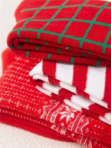 Detailed view of red Christmas knit socks with plaid, striped, and snowflake patterns