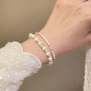 Detail of French style pearl bead and silver link bracelets worn on a wrist with polka dot cuff