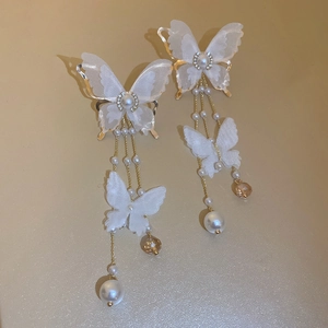Macro detail of long tassel earrings with lace butterflies, pearls, and sparkling rhinestones
