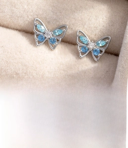 Macro shot of silver butterfly cartilage piercing studs with blue zircon inlays