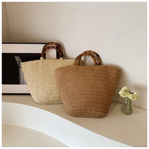 Detail of woven straw tote bags in beige and khaki with natural bamboo handles