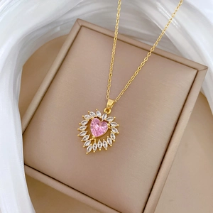 Close-up of gold heart necklace with pink zircon and marquise stones on jewelry box