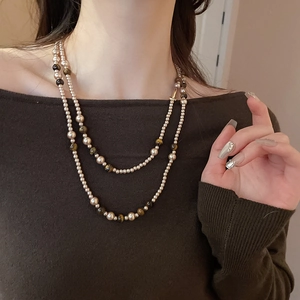 Dettaglio della collana a doppio strato con occhio di tigre e perle indossata da modella