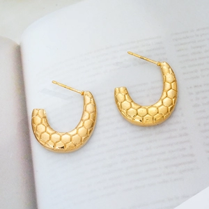 Macro detail of 18K gold plated C-shaped earrings with unique hexagonal honeycomb texture