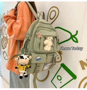 Dettaglio dello zaino in nylon verde chiaro con multitasche e ciondolo orsetto