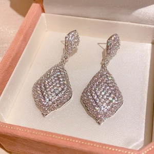 Gros plan de boucles d'oreilles goutte avec zircons blancs sur une boîte à bijoux rose