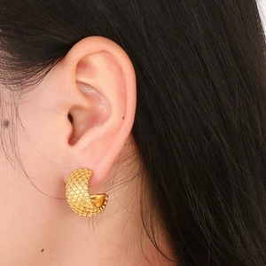 Close-up of golden mesh texture C-shaped titanium steel earring worn by model on ear