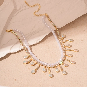 Double-layered pearl necklace with colorful drop crystals on beige stone background