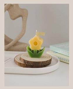 Macro detail of a yellow flower-shaped candle on a rustic wooden tray decoration