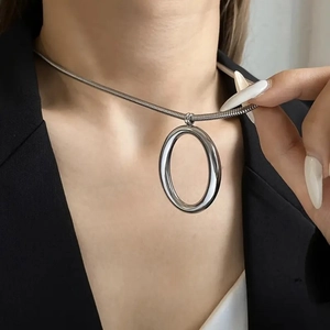 Close-up of minimalist silver stainless steel snake chain necklace with oval pendant on neck