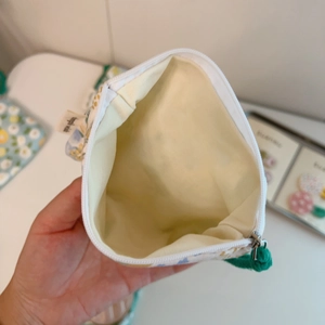Detail of the green floral cotton pouch showing interior lining and zipper closure