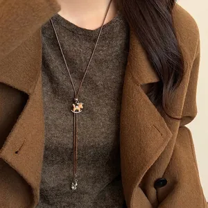 Minimalist pearl necklace with tiger eye horse pendant on a brown cord sweater chain