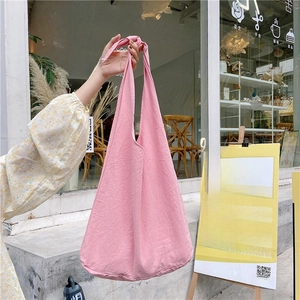 Detailed texture of a pink fabric hobo bag with a decorative knotted shoulder strap