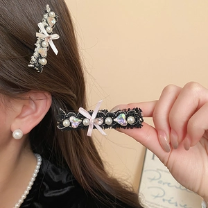 Detail of a pearl bow hair clip with pink ribbon and sparkling heart rhinestone accent