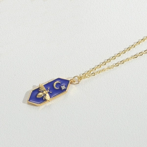 Detail of gold bee necklace with crescent moon star and blue hexagonal enamel pendant