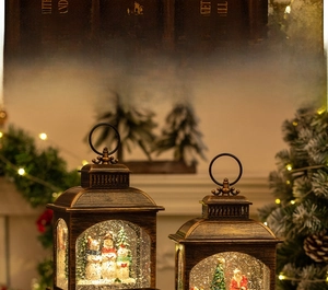Close-up of lighted vintage bronze Christmas lanterns with snowman and Santa scenes