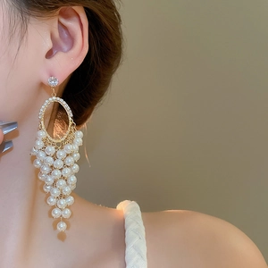 Close-up of pearl grape cluster tassel earrings worn by a model in soft lighting