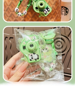 Detail of green panda camera keychain with decorative chain in clear packaging