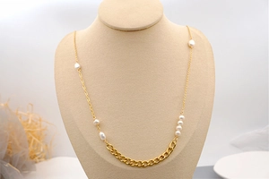 Detail showing asymmetrical gold chain with freshwater pearls on a display stand
