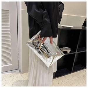 Detail of silver crocodile embossed envelope clutch with elegant gold metal trim