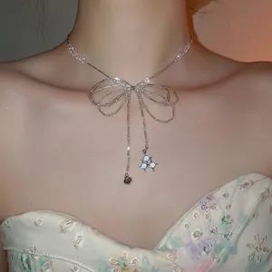 Silver beaded bow necklace with dangling heart and blue star pendants on female model