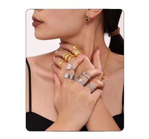 Close-up of stacked gold and silver textured rings on model's hand with fashion accessories