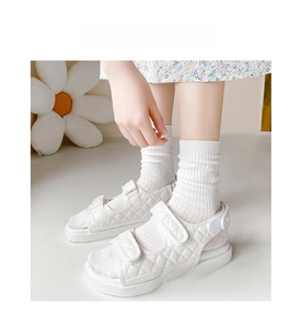 Close-up of white ribbed crew socks paired with quilted sandals for a casual spring look
