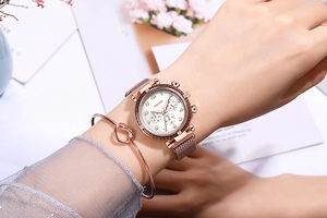 Détail de la montre à maille or rose et du bracelet à nœud assorti portés au poignet