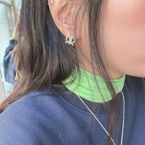 Silver-tone knot heart earrings on model with a textured surface and minimalist style