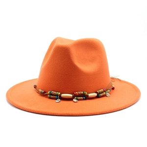 Détail du chapeau en laine orange avec ruban perlé ethnique et pendentifs en métal